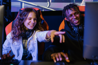 Students laughing and smiling while playing video games on the computer.