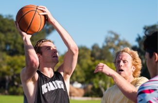 Man holding a basketball in hand, ready to shoot into the hoop.